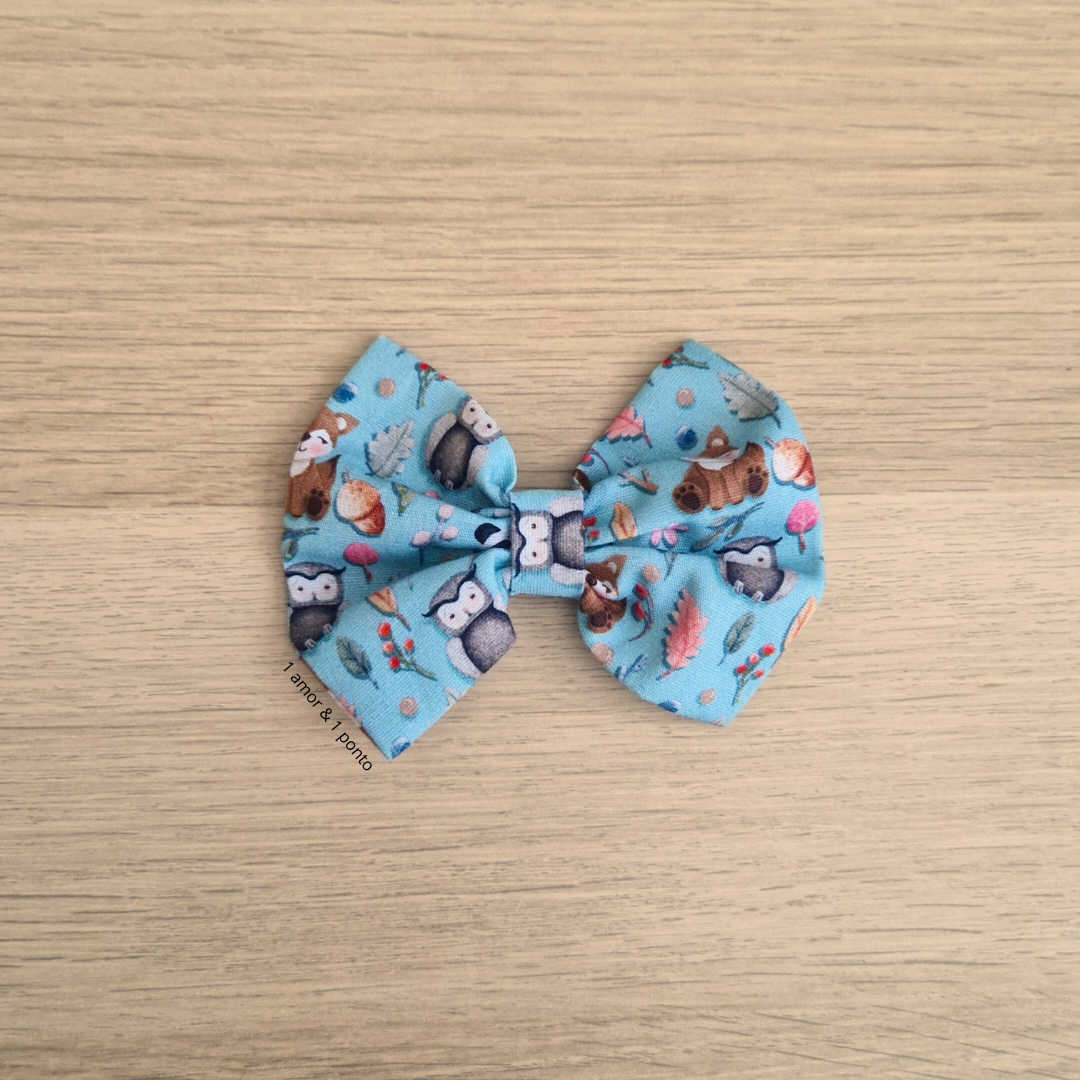 Laço de tecido azul com padrão de animais da floresta sobre madeira clara