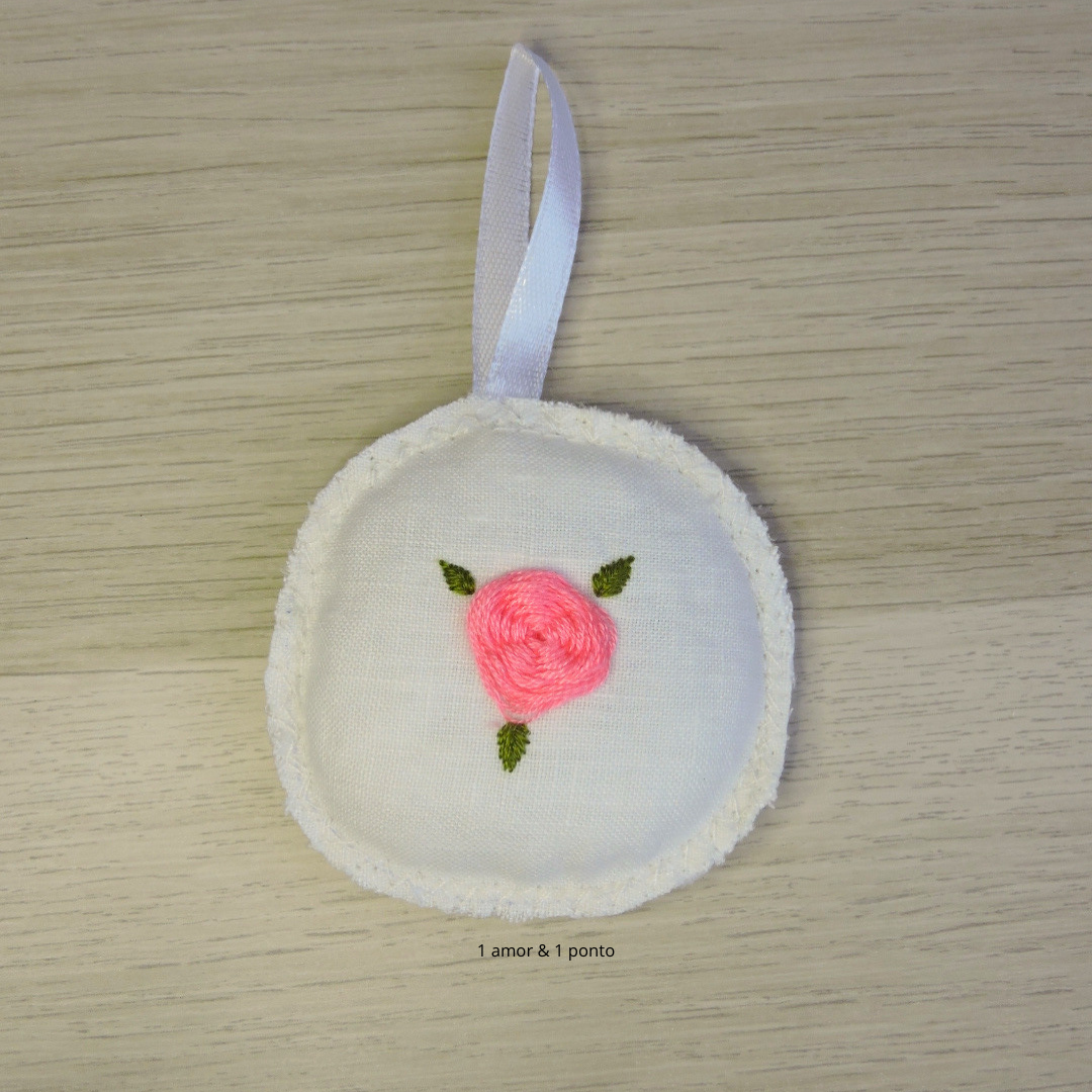 Ornamento redondo em tecido branco com bordado de rosa cor-de-rosa e fita branca