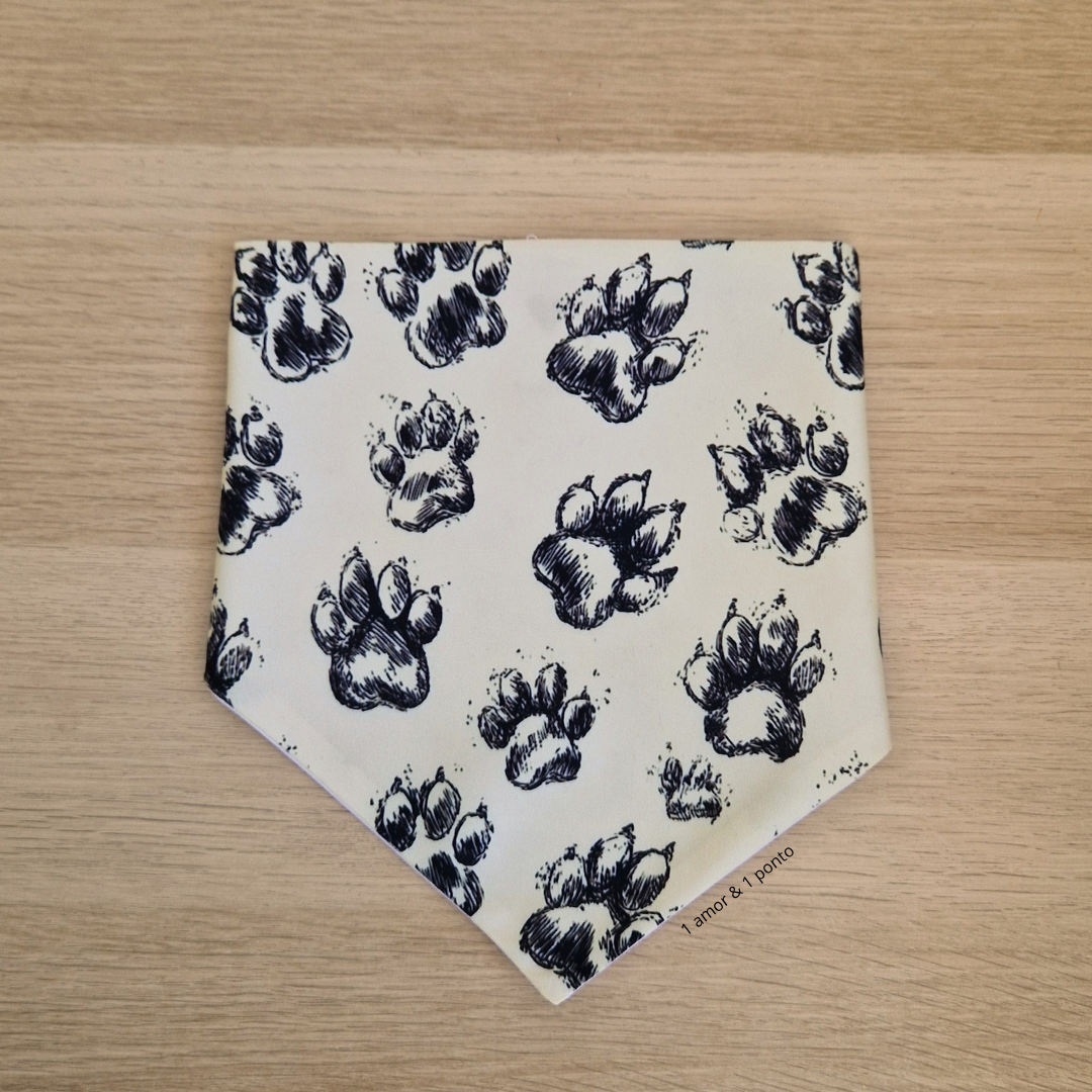 Bandana branca com pegadas de patas pretas sobre madeira clara