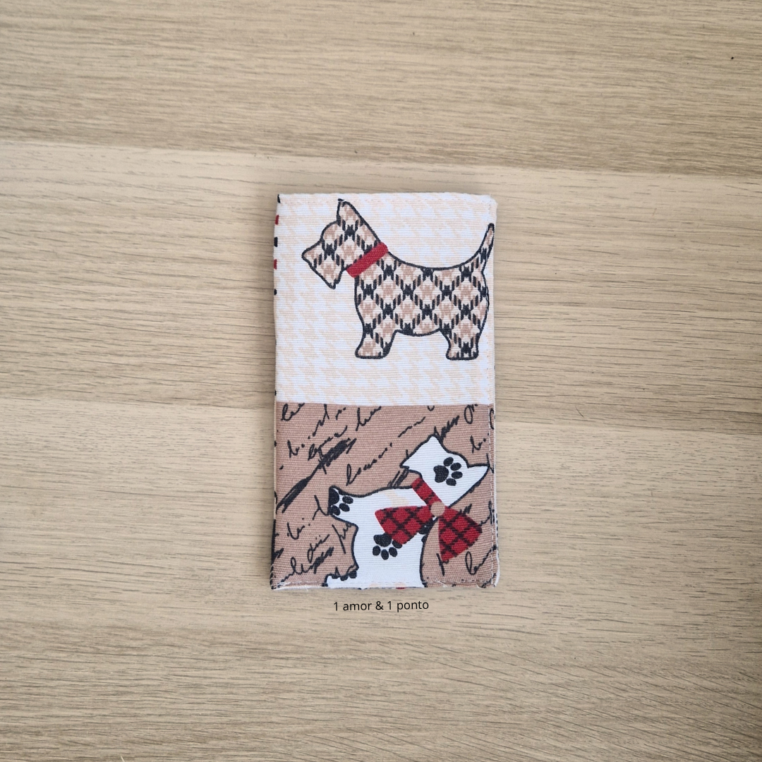Carteira de tecido com desenho de cães sobre madeira clara
