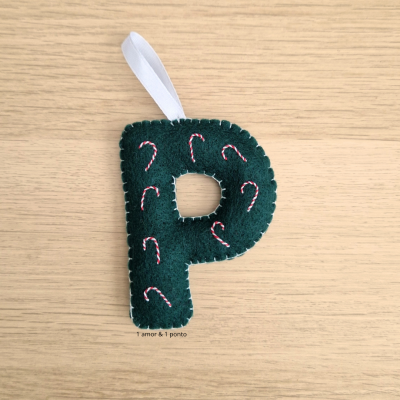 Ornamento de Natal em forma de letra P em tecido verde escuro com bordados vermelhos e brancos.
