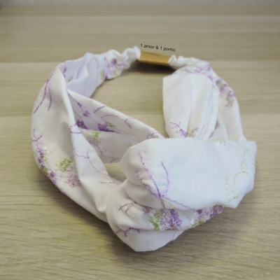 Faixa de tecido com estampas florais e etiqueta com texto sobre madeira