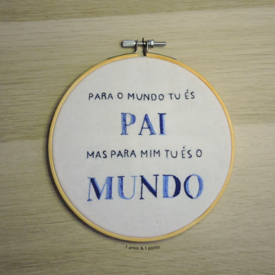 Bordado redondo com frase em português sobre pai, em tecido branco com moldura de madeira
