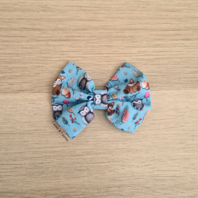 Laço de tecido azul com padrão de animais da floresta sobre madeira clara