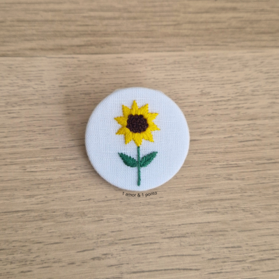 Botão redondo com bordado de girassol sobre fundo branco