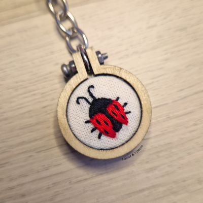 Chaveiro em madeira com bordado de joaninha vermelho e preto em tecido branco