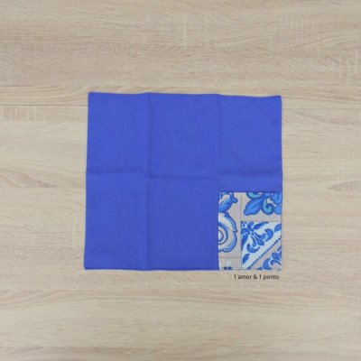 Guardanapo azul com padrão azul e branco num canto sobre madeira clara