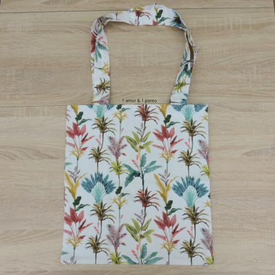 Saco de tecido branco com padrão floral colorido e alças iguais sobre madeira