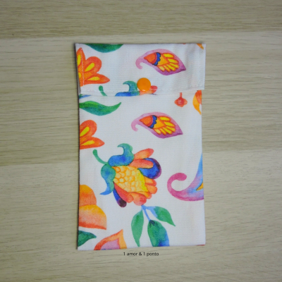 Estojo de tecido branco com padrão floral colorido e botão laranja