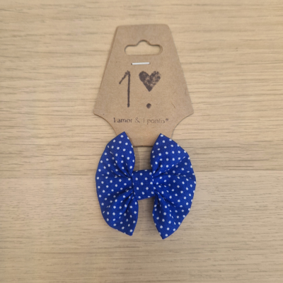 Laço de cabelo azul com bolinhas brancas em cartão castanho com texto