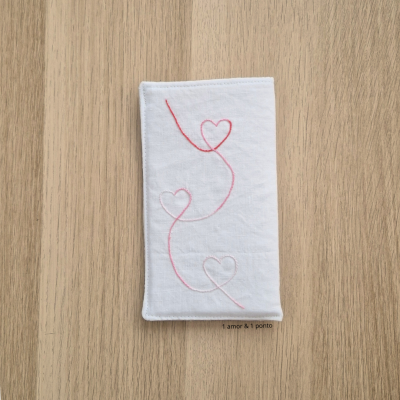 Toalha branca com bordado de corações cor-de-rosa sobre madeira clara
