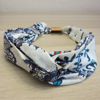 Faixa de cabelo floral azul, branca e vermelha em superfície de madeira