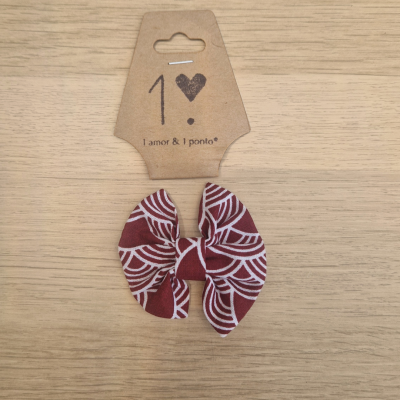 Laço de tecido vermelho com padrão branco e cartão castanho com texto