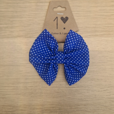 Laço azul com bolinhas brancas em cartão castanho sobre fundo de madeira clara