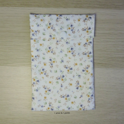 Bolsa de tecido floral com fecho branco sobre madeira clara