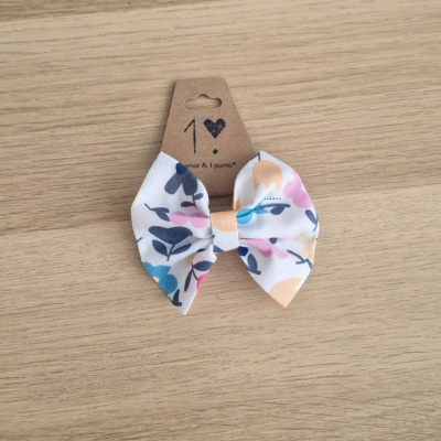 Laço de tecido branco com padrão floral colorido em cartão castanho sobre madeira clara