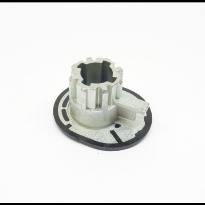 Peça metálica prateada com base circular preta e dentes verticais sobre fundo branco