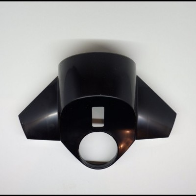 Peça plástica preta com orifícios em forma circular e retangular sobre fundo branco