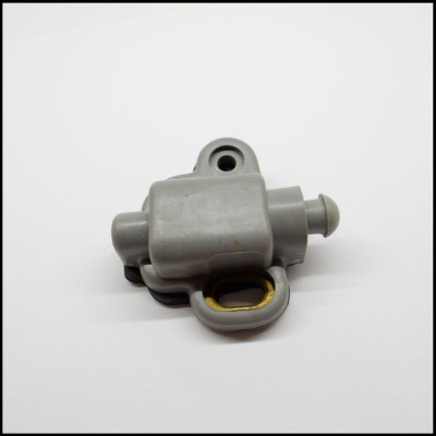 Peça mecânica pequena de plástico cinzento com detalhe amarelo sobre fundo branco