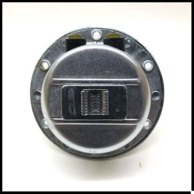 Tampa metálica redonda com mola e parafusos numa superfície branca