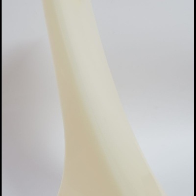 Peça alongada creme de plástico com contornos curvos sobre fundo branco