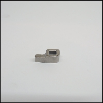 Pequena peça metálica cinzenta com orifício quadrado