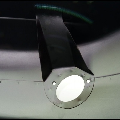 Peça metálica com furo circular no centro em fundo cinzento