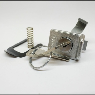 Cadeado metálico prateado com chave e mola em fundo branco