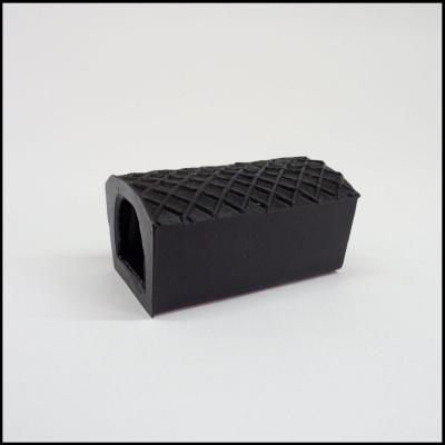 Peça de borracha preta retangular com padrão texturizado e buraco evidente