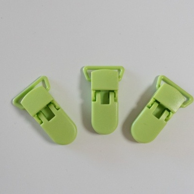 Três clips de plástico verde clara com mecanismo articulado sobre superfície branca