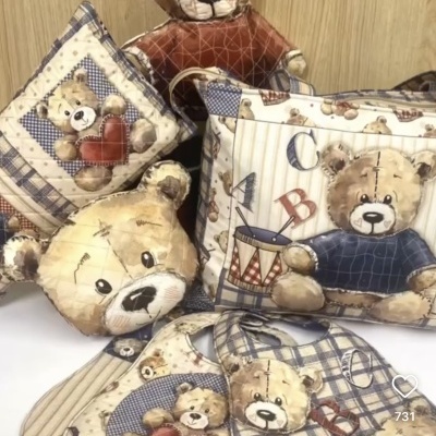 Conjunto decorativo com almofadas e acessórios com padrão de ursinhos em bege, azul, vermelho e castanho.