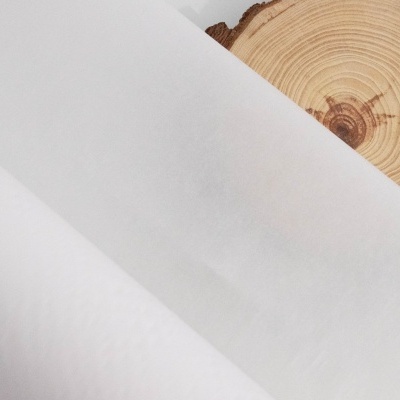 Papel de seda branco sobre fatia redonda de madeira com anéis visíveis