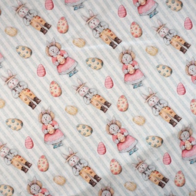 tecido com padrão de coelhos e ovos de páscoa em tons pastel sobre fundo listrado azul e branco