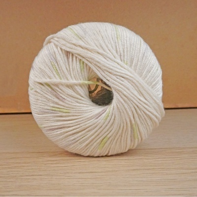 Novelo de lã branca com manchas amarelas numa superfície de madeira clara