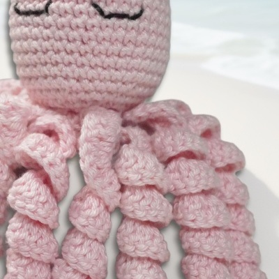 Boneco de polvo de crochet rosa claro com tentáculos enrolados