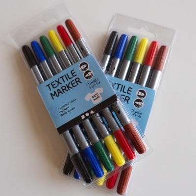 Dois conjuntos de marcadores têxteis coloridos em embalagem plástica com rótulo azul