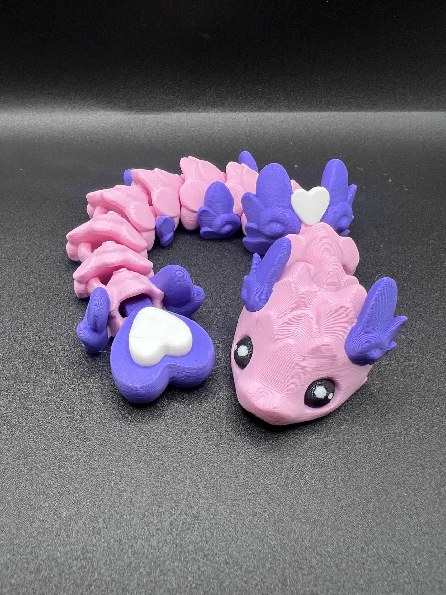 Figura de dragão cor-de-rosa e roxo com corações brancos