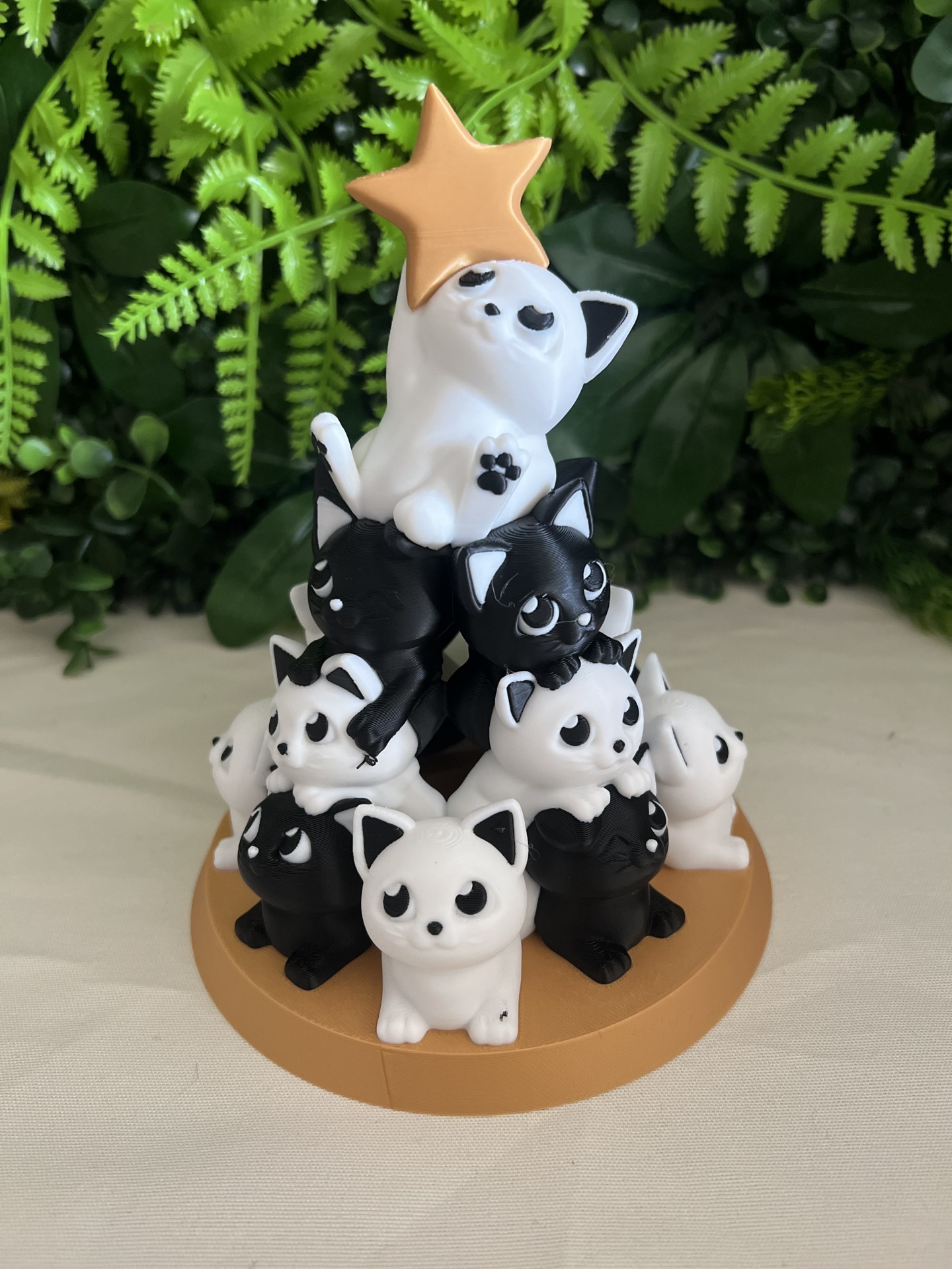 Escultura de gatos em forma de pirâmide com estrela dourada no topo.