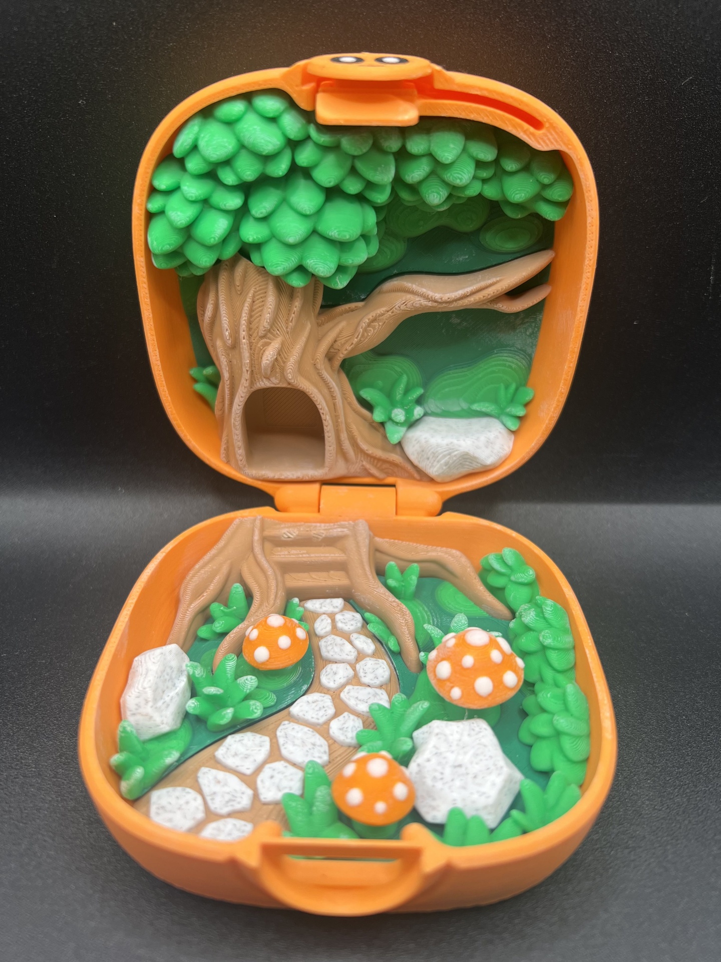 Playset portátil com cenário de floresta com árvore, cogumelos e pedras em cores vivas.