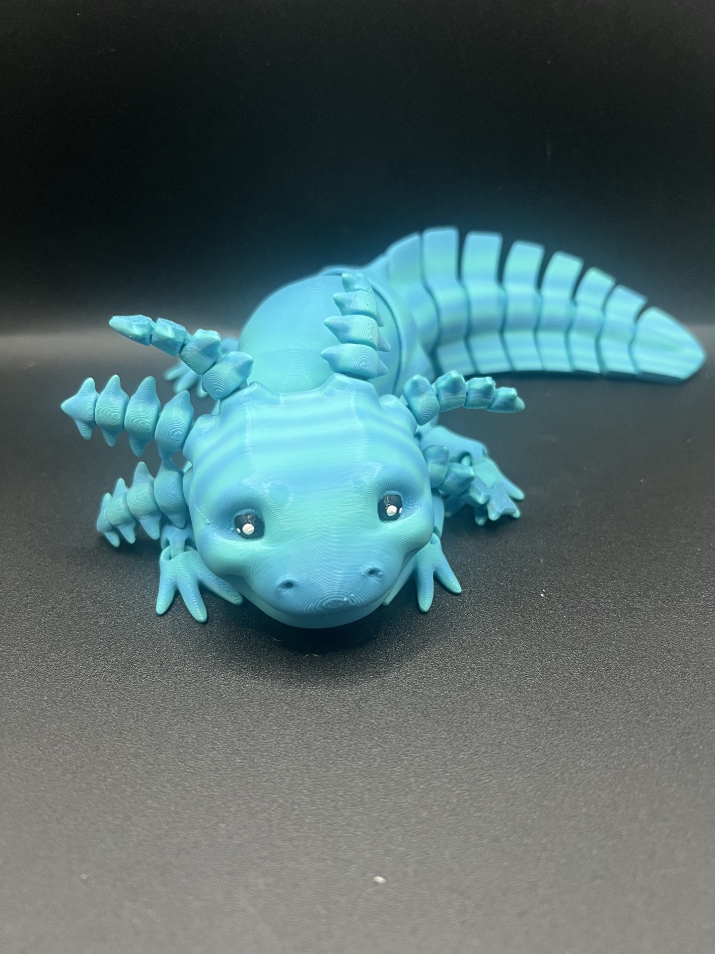 Figura miniatura de axolote azul com olhos negros em fundo preto