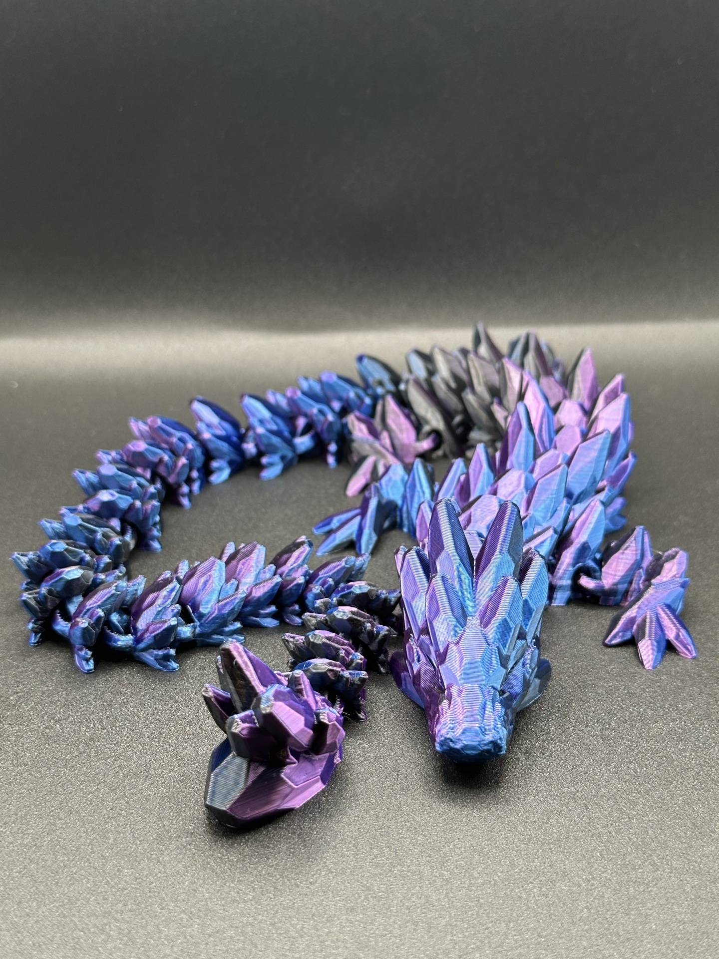 Figura decorativa de dragão azul, roxo e preto com textura facetada