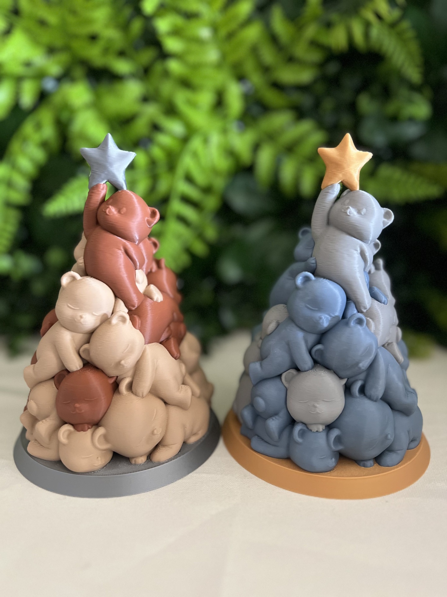 Objetos decorativos em forma de pirâmide de ursinhos empilhados em tons terra e azul com estrelas no topo.