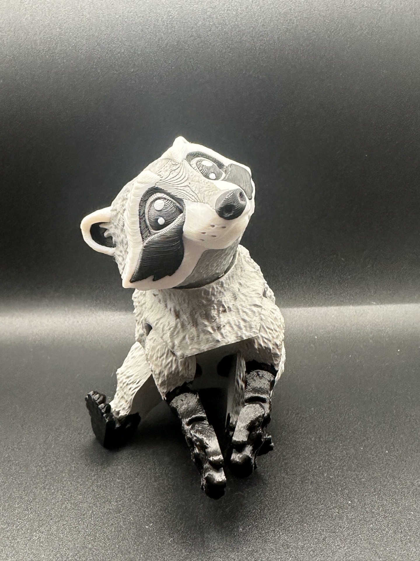 Boneco de guaxinim estilizado em material plástico cinza, branco e preto