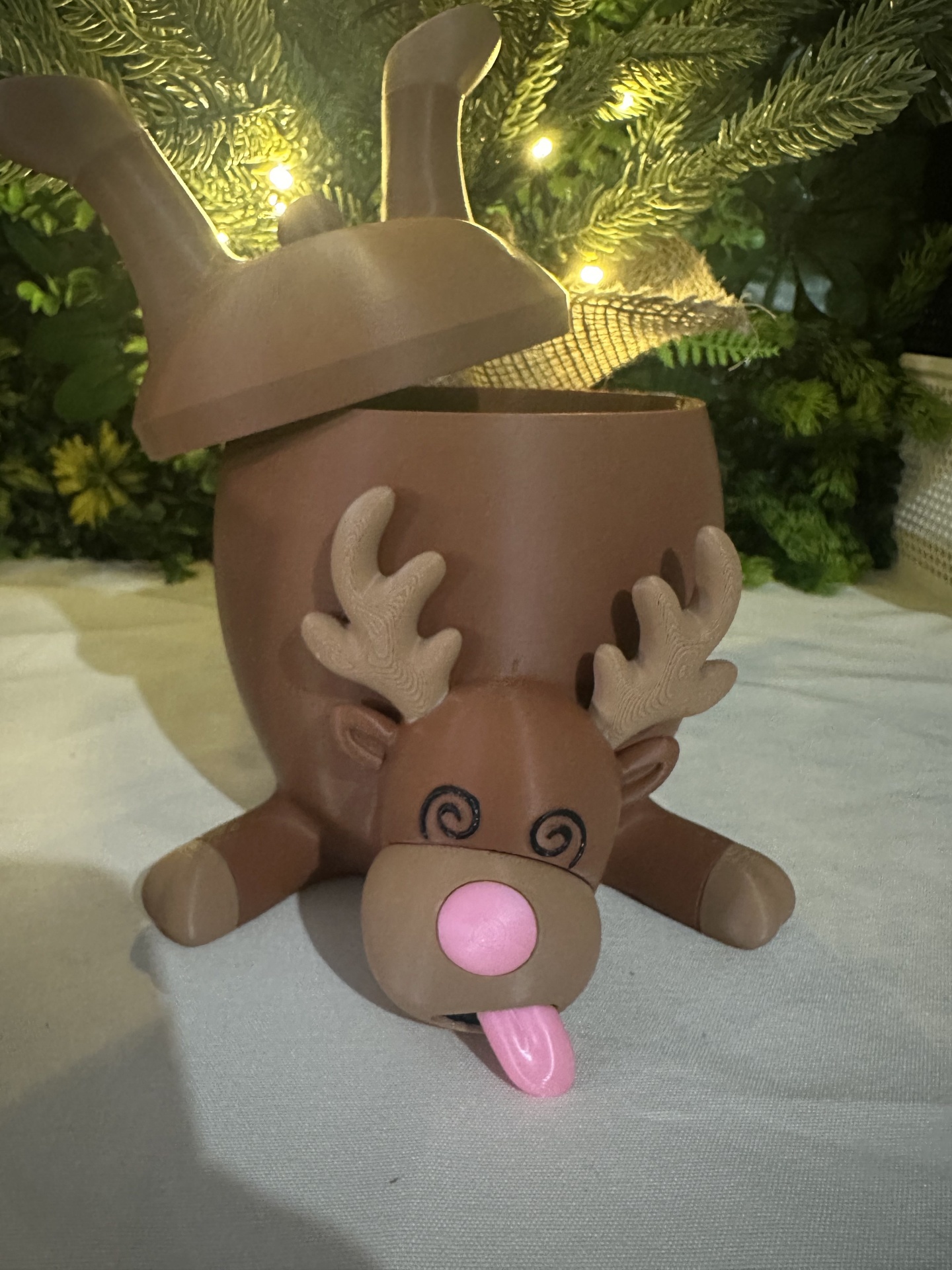 Caixa decorativa em forma de rena castanha com nariz rosa e língua cor-de-rosa