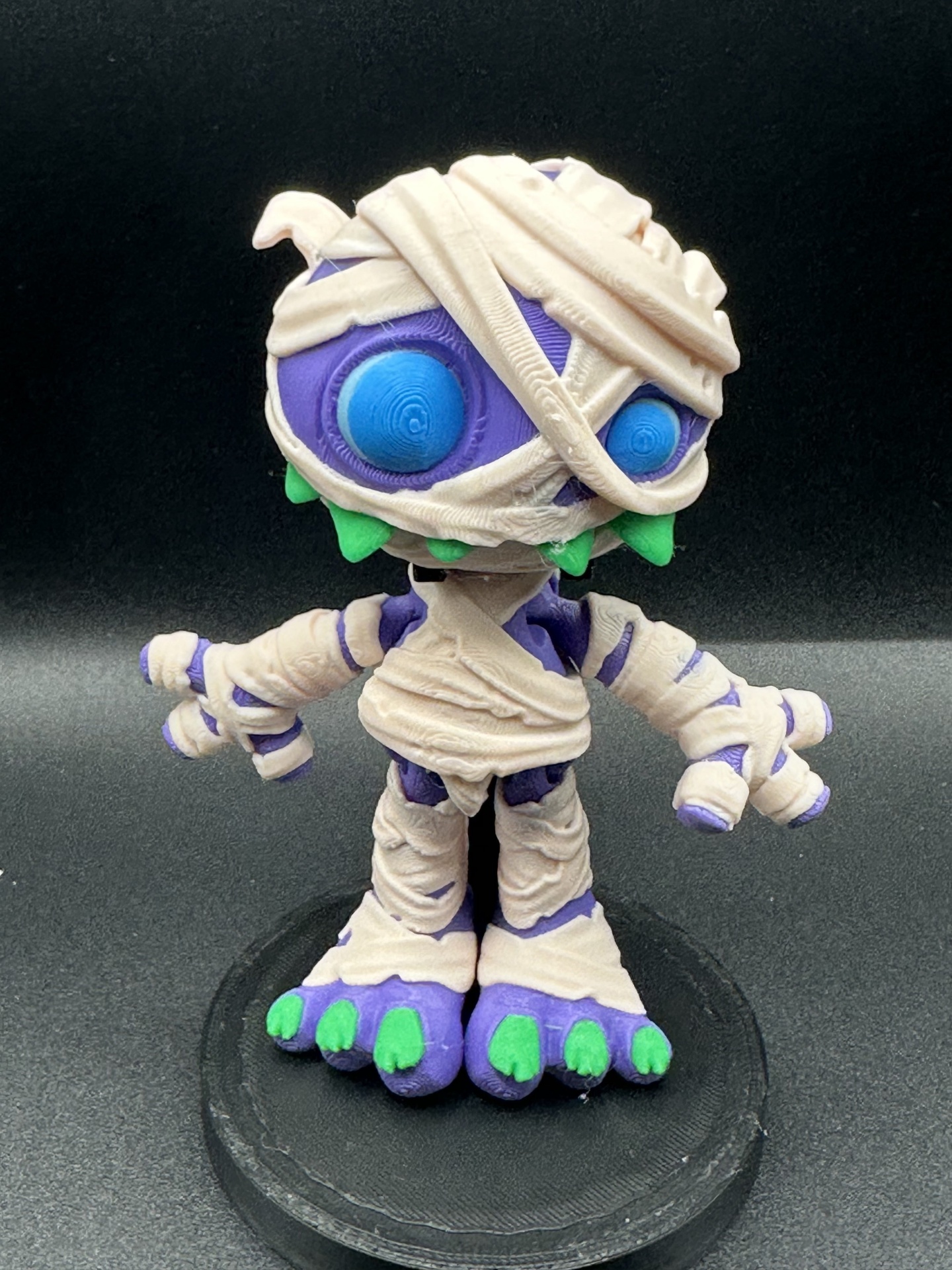 Figura de vinil de múmia roxa com faixas bege e unhas verdes