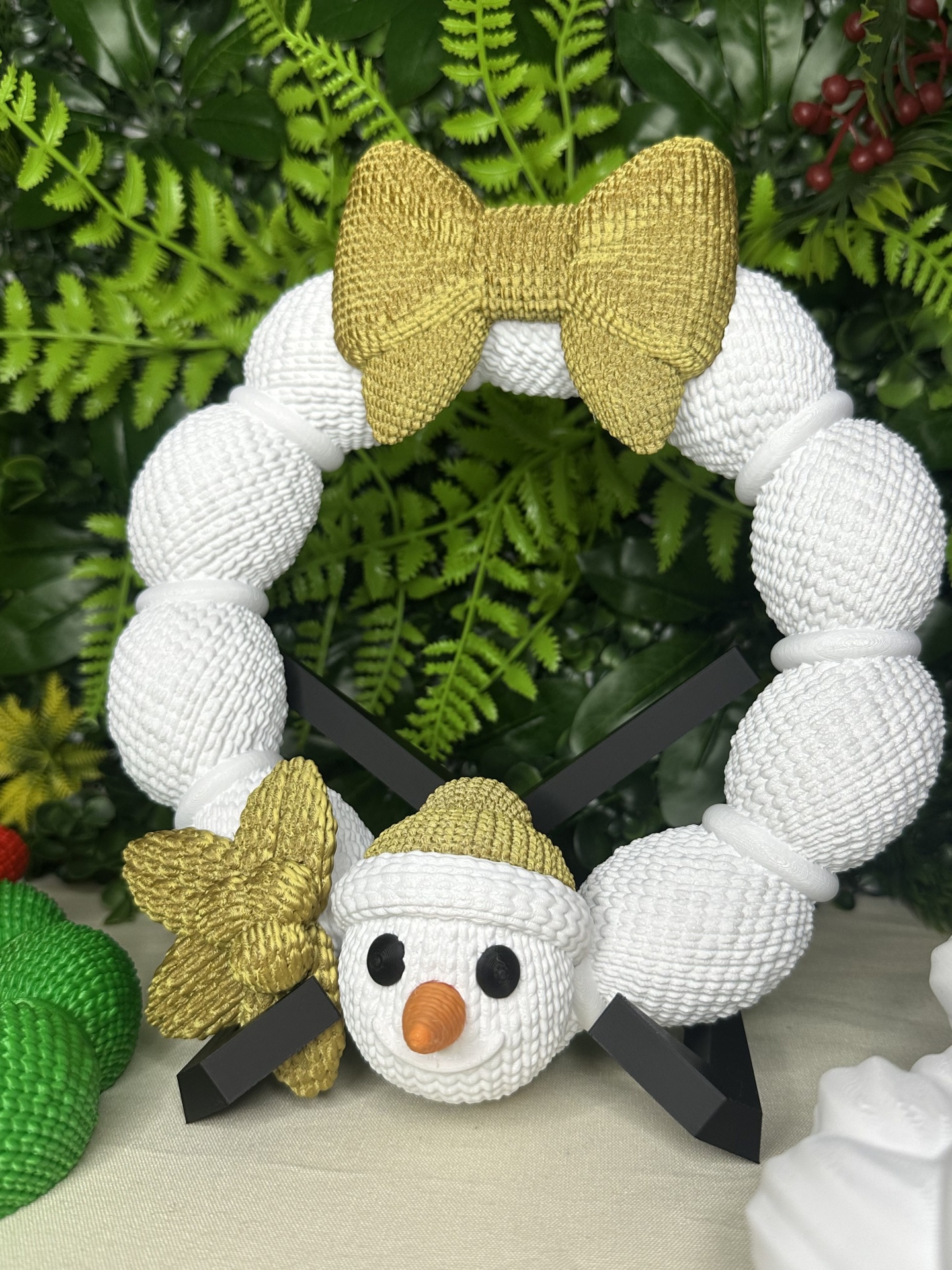 Guirlanda decorativa branca com laço dourado e rosto de boneco de neve em suporte