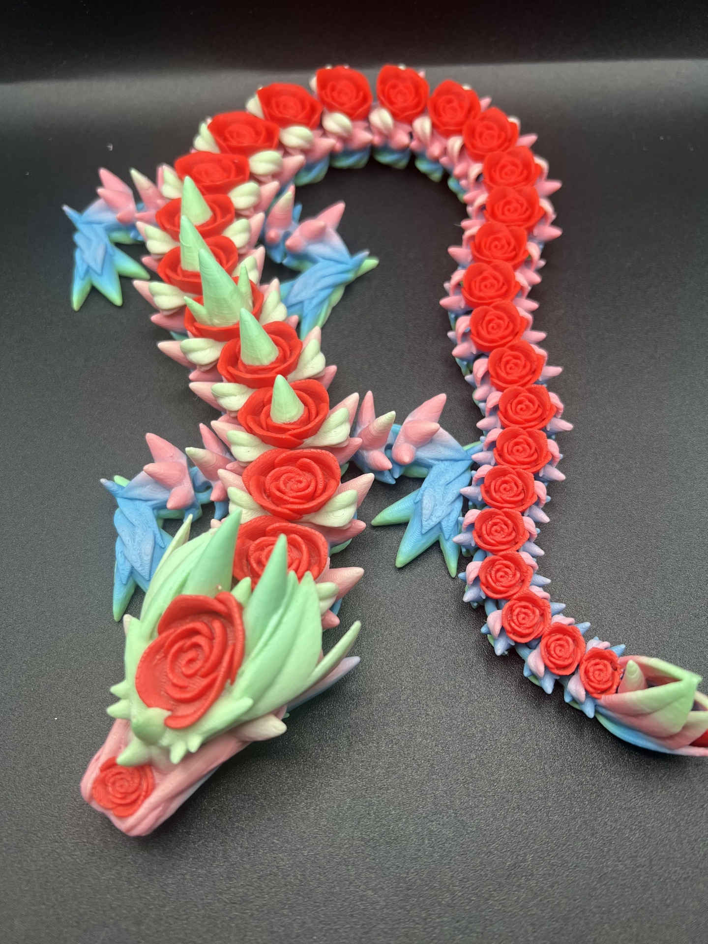 Escultura decorativa de dragão em várias cores sobre fundo preto