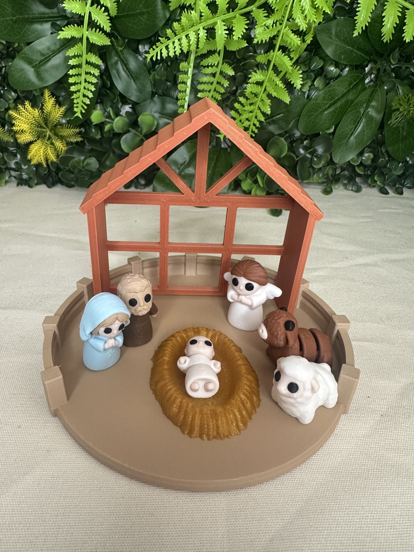 Miniatura presépio de Natal em plástico com manjedoura, figuras e estábulo castanho sobre mesa clara