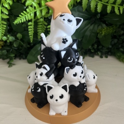 Escultura de gatos em forma de pirâmide com estrela dourada no topo.