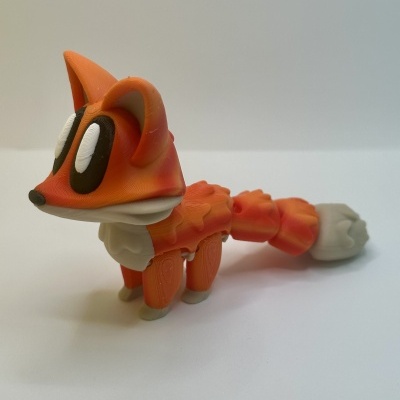 Figura de raposa laranja em material plástico com olhos grandes e cauda segmentada